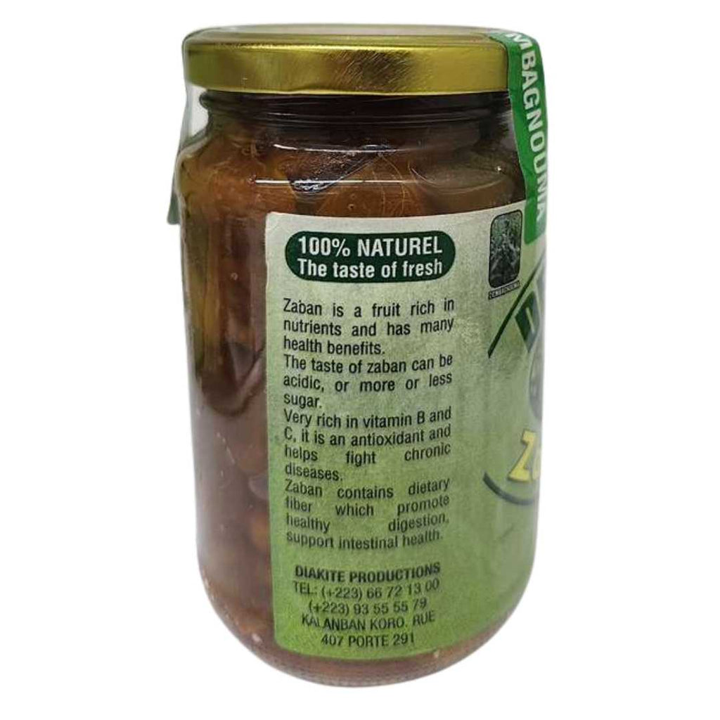 Glass jar of DEMBAGNOUNA Zaban Duman with a gold lid and green label. The label features an image of African locust fruits (zaban) hanging on a tree branch, with text reading “Made in Mali,” “Net Wt: 18 oz,” and “Exp Date: 07/2026.”