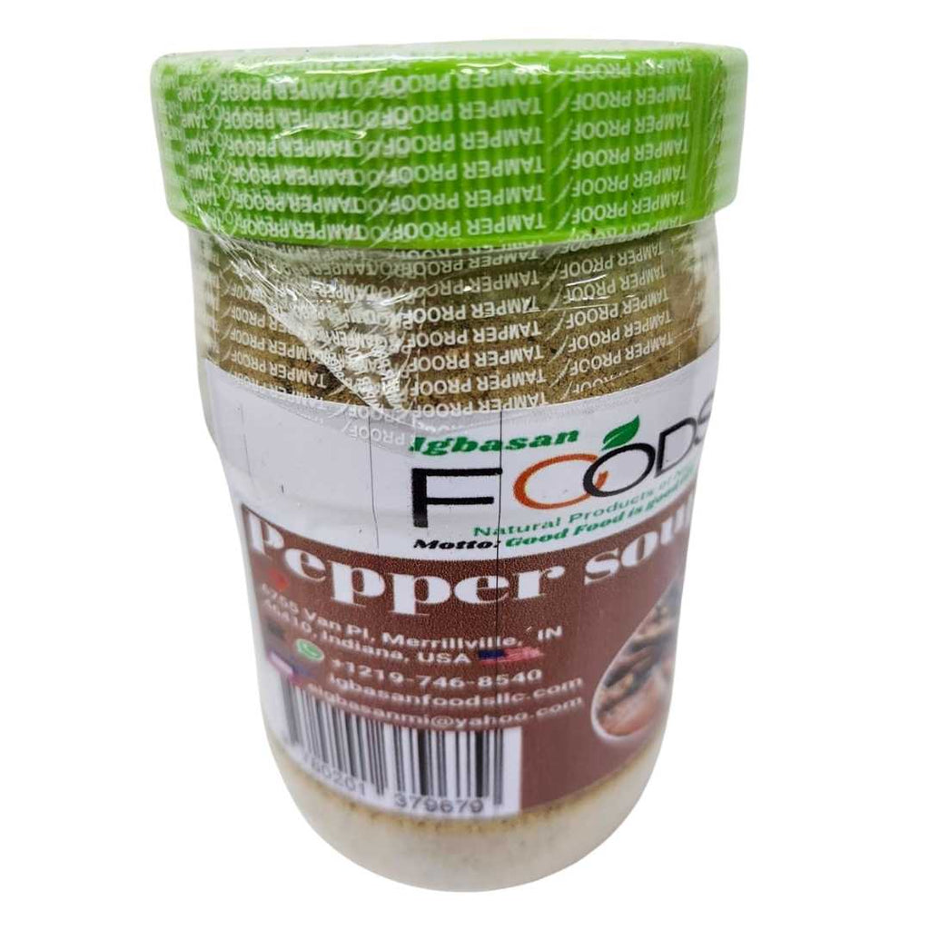 A sealed jar of Igbasan Foods Pepper Soup Mix with a green tamper-proof lid and a brown label featuring an image of a traditional Nigerian pepper soup dish. The label includes the Igbasan Foods logo, contact details, and barcode.