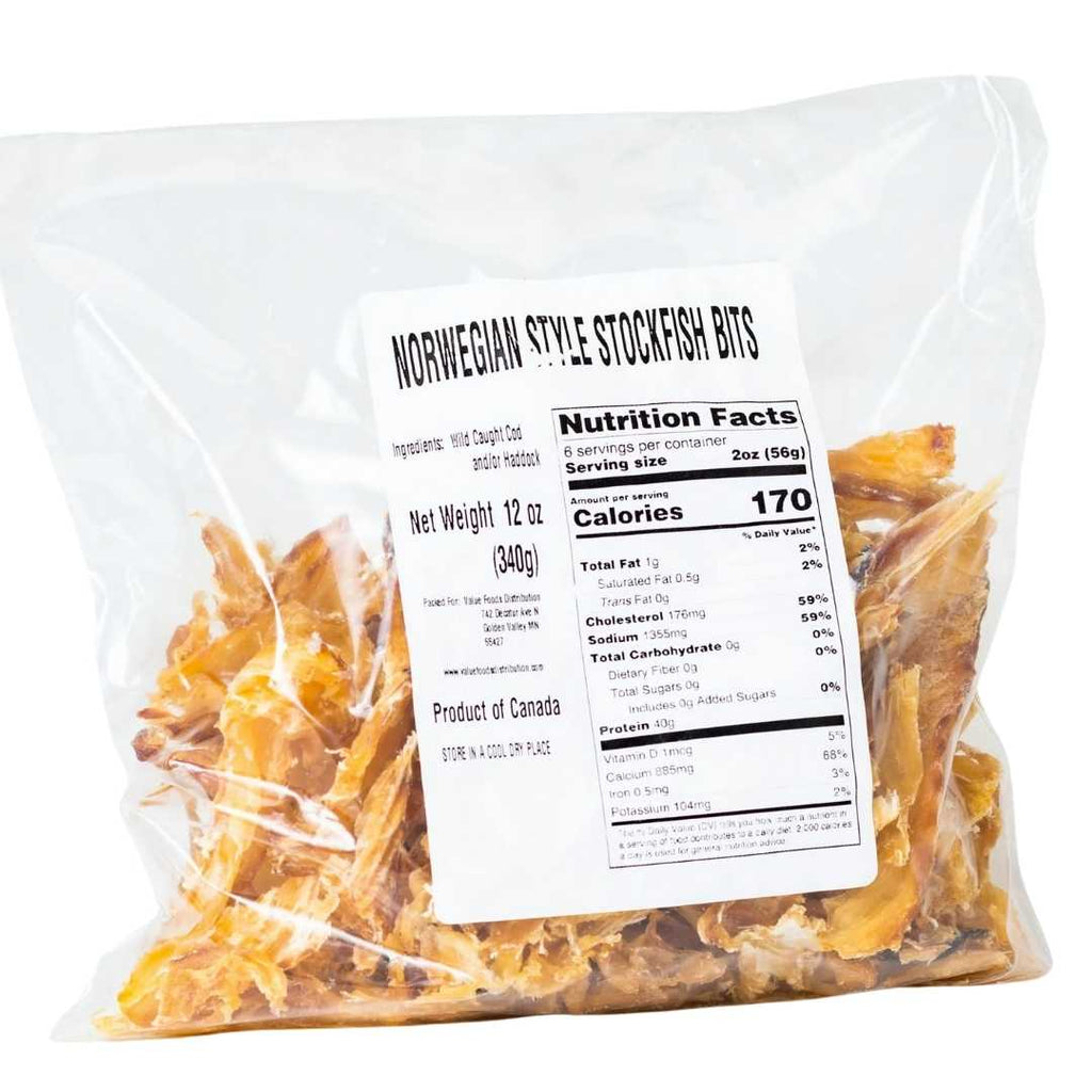 Dried Norwegian stockfish bits on a rustic wooden surface, showcasing their light beige color and rough texture.